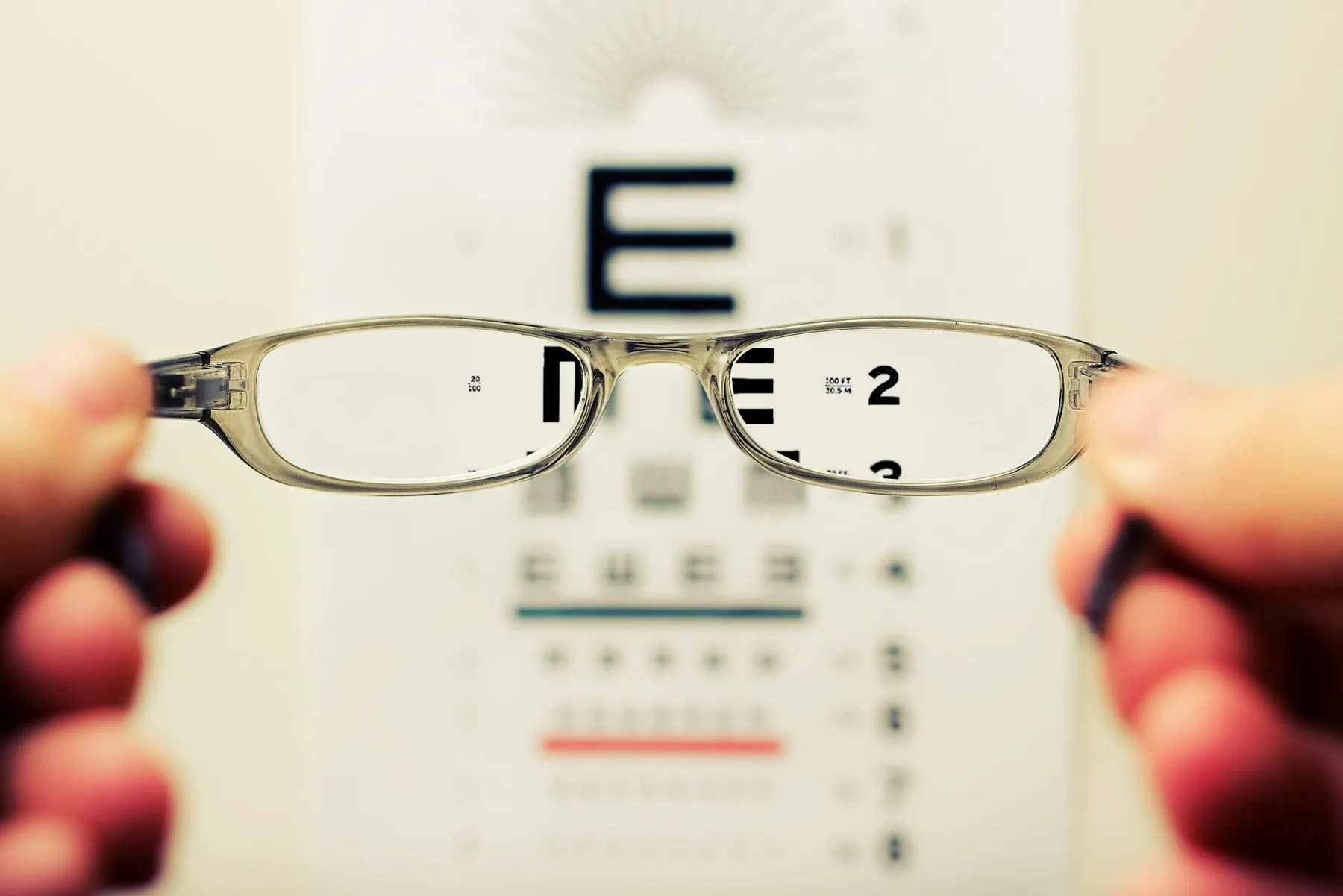 A person holding a pair of black-framed prescription eyeglasses