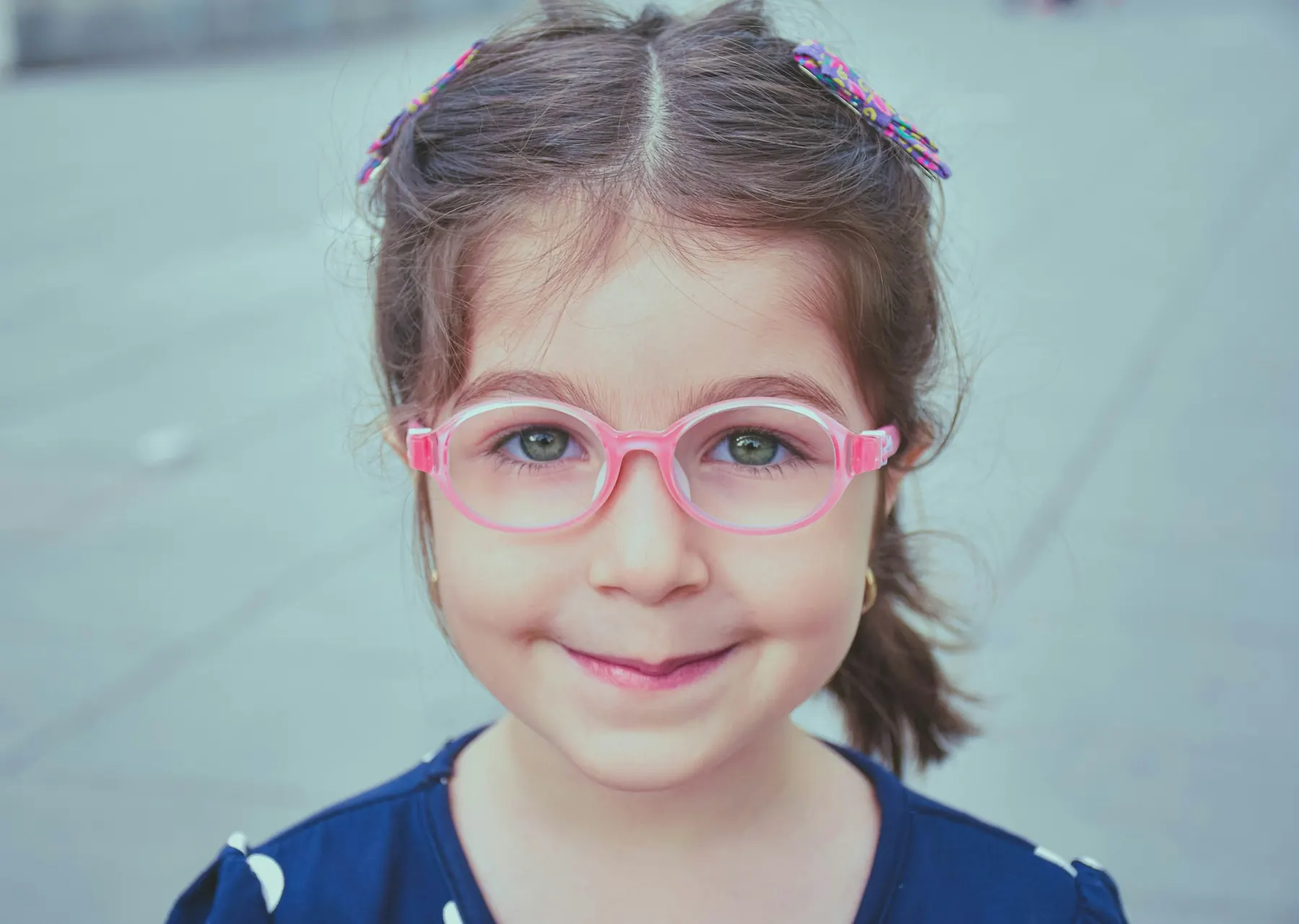 A young girl wearing her first pair of pink-framed glasses
